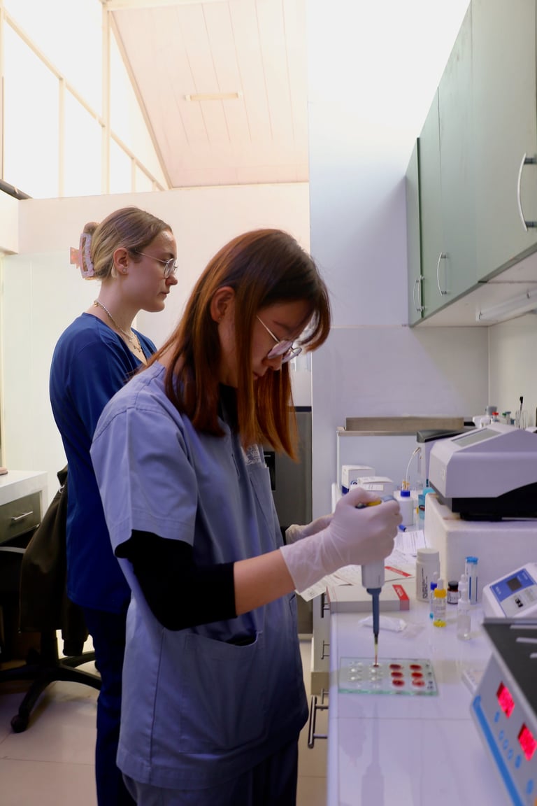 Two scientists in lab coats working with laboratory equipment and samples at a bench in a modern research facility.