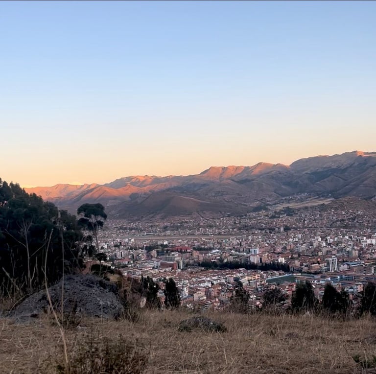 Expansive valley city nestled between mountains at sunset with golden light illuminating the peaks and urban sprawl below