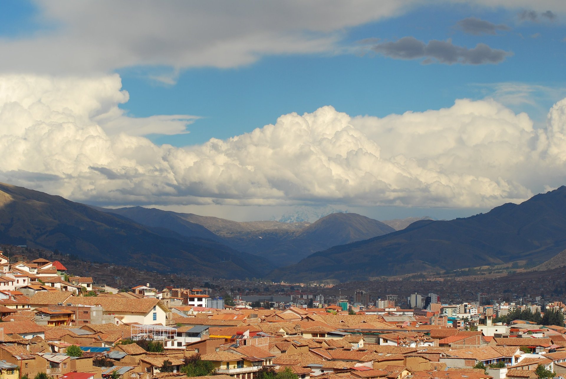 Sprawling city nestled in a valley surrounded by mountains and dramatic clouds in the sky