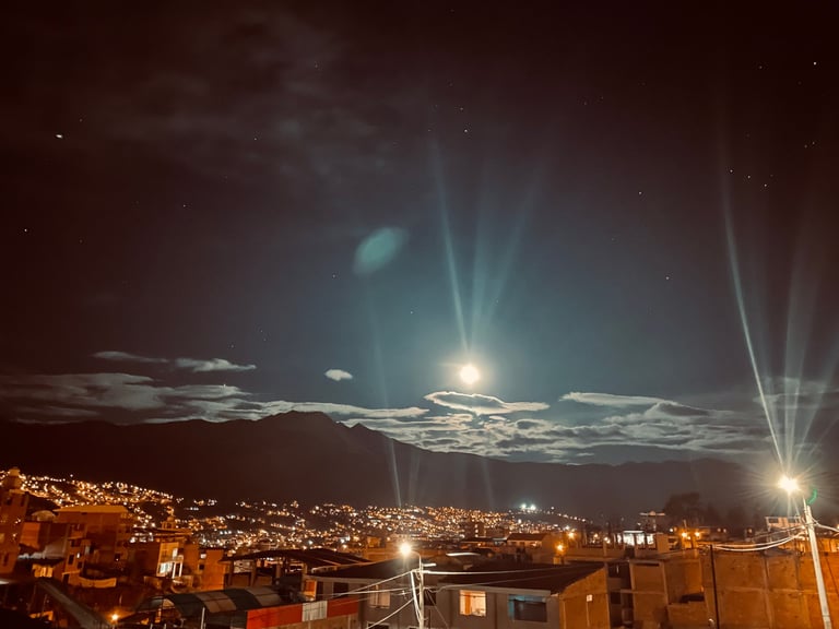 Bright light phenomenon in night sky above illuminated city buildings with dramatic light rays