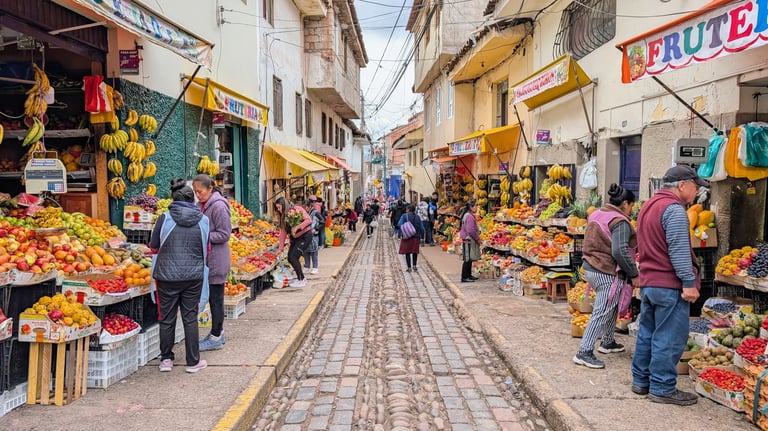 Busy outdoor market street lined with produce stalls displaying fresh fruits and vegetables, with shoppers walking among colorful displays