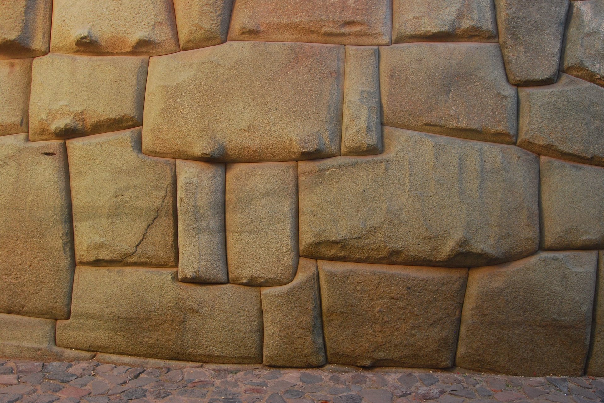 Close-up of precisely fitted stone masonry wall with rectangular golden-brown blocks arranged in an interlocking pattern without mortar