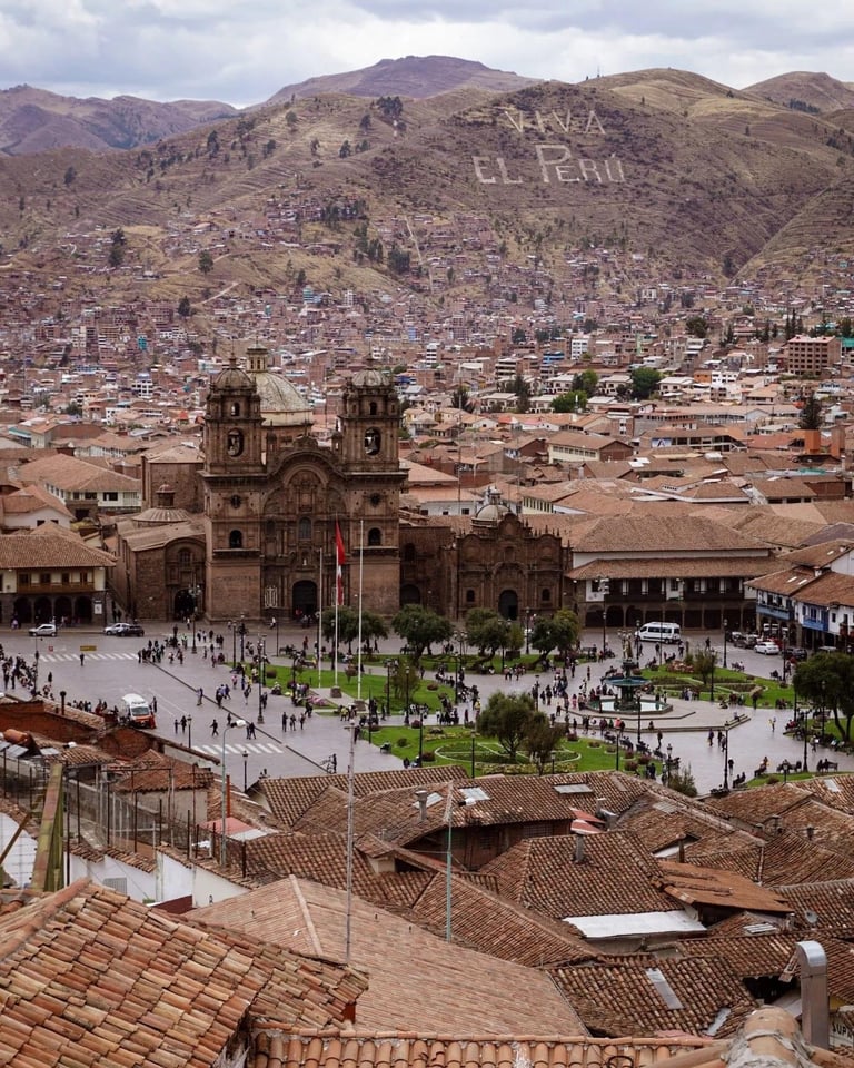 Cathedral in Cusco's main plaza with surrounding colonial buildings and Andes mountains in background
